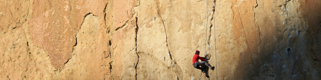 A man climbing on a rock wall with a rope.