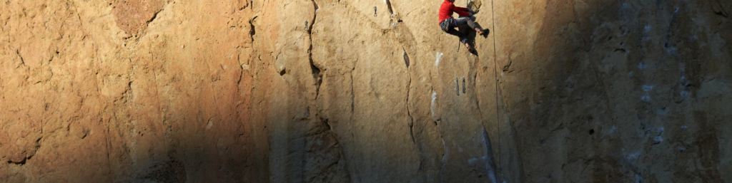 A man climbing on a rock wall with a rope.