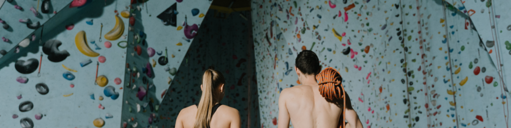 A man and a woman standing next to each other observing a bouldering wall.